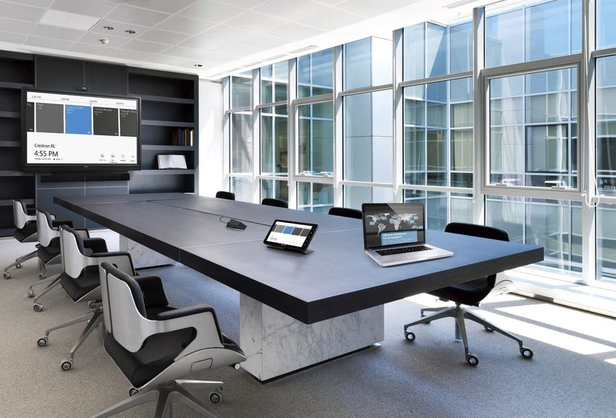 A conference room with a a large screen at the far end and large windows.